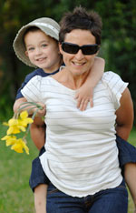 A woman piggybacks a young boy with daffodils