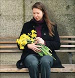 A woman with daffodils sitting on a bench
